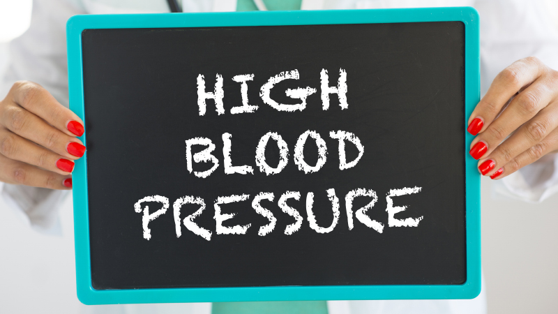 white lab coat woman holding chalkboard sign saying High Blood Pressure