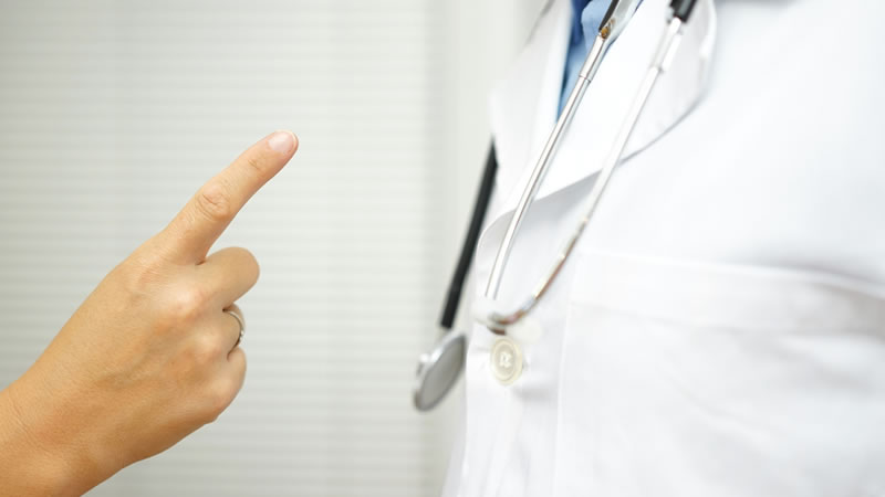 finger pointing as if in blame at white lab coat and stethoscope