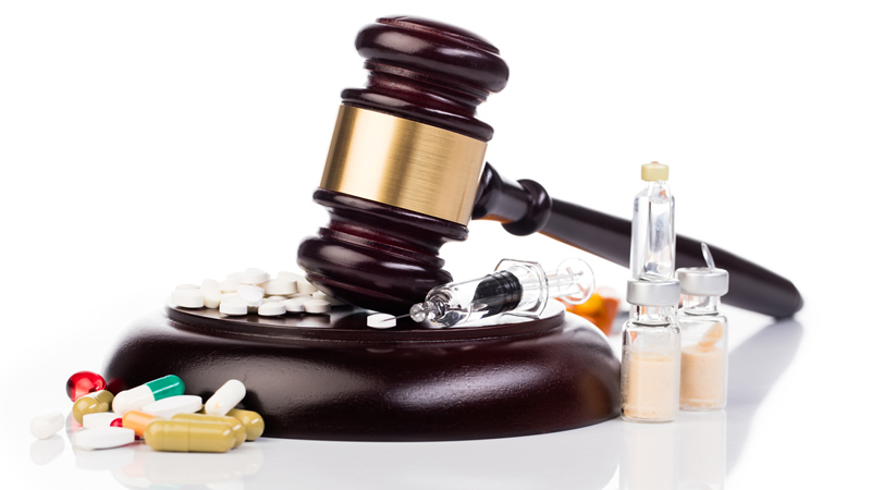 gavel and block with hypodermic needle, tablets and capsules