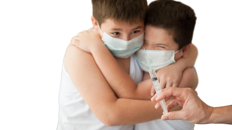two masked young boys hugging each other in fear of hypodermic needle