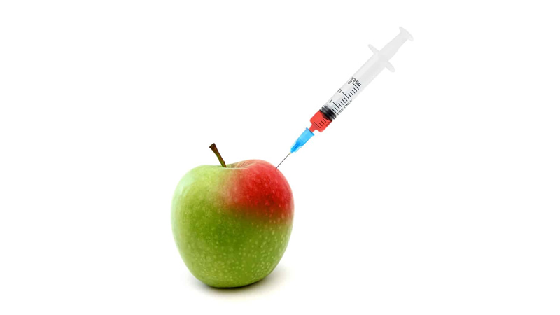 hypodermic needle going into an apple
