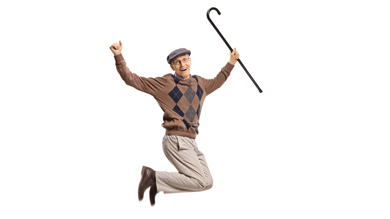 older fit happy man jumping with cane in hand and arms up