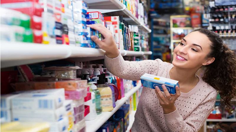 smiling woman choosing product off full shelf in store