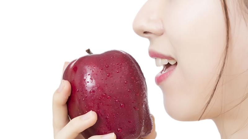 close up of woman about to bite into red apple