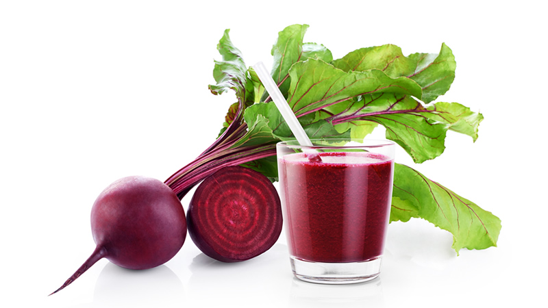 whole beet with green top and half beet and glass beet juice