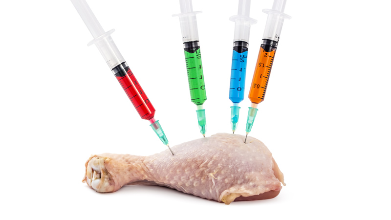 raw chicken drumstick with 4 hypodermic needles inserted filled with assorted colored liquid