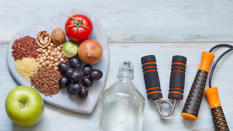 grains and fruit on heart-shaped plate with water bottle and exercise equipement
