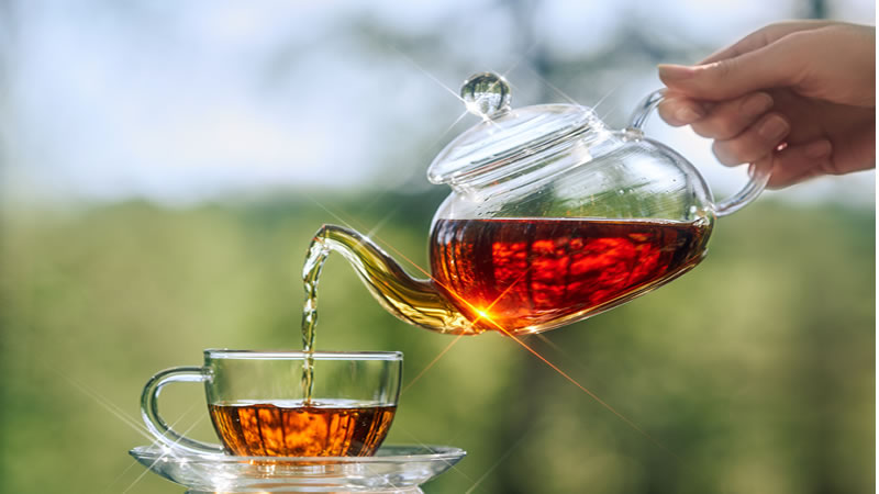 Glass tea pot pouring into glass cup