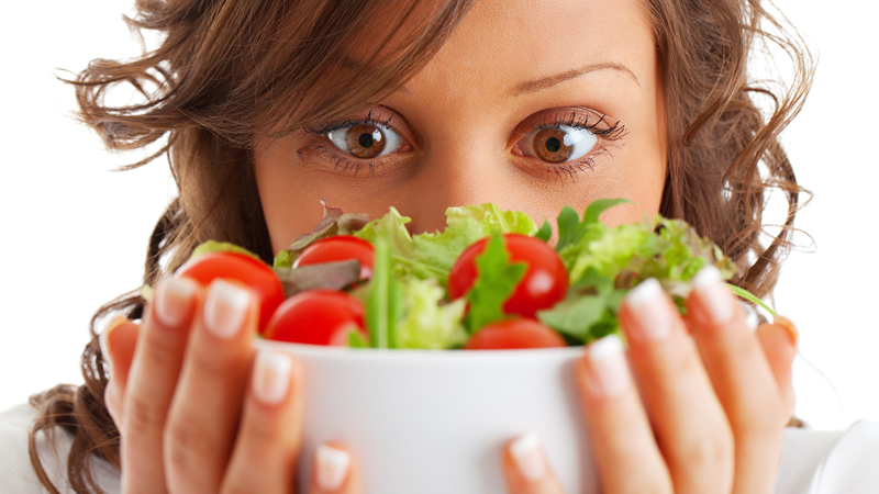 womans big brown eyes staring into salad bowl shes holding