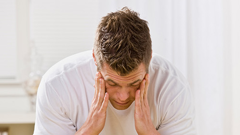 man bent over holding his head as if in pain