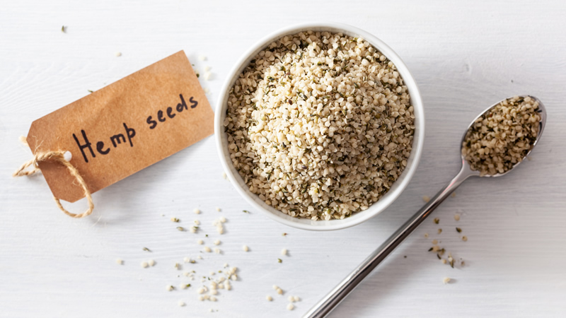 top view tag saying Hemp seeds with small white bowl and spoon full of hemp seeds