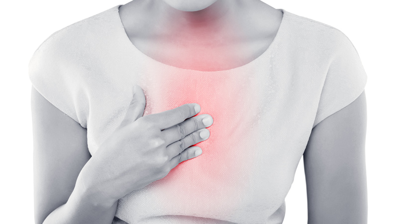 woman with hand on redish chest as if with heartburn