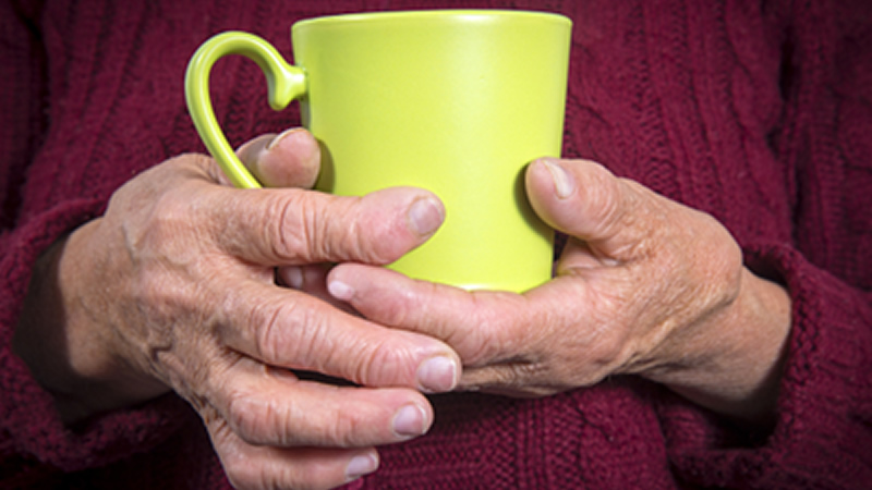 older arthritic hands holding mug