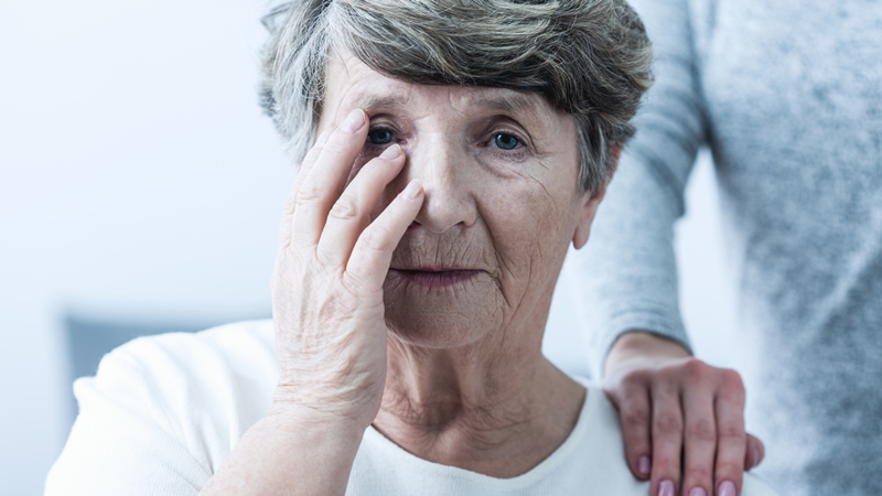 head of older woman, hand on face as if in pain