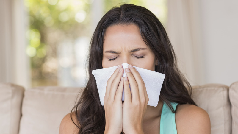 woman with tissue covering nose and mouth as if to sneeze
