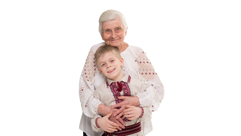 front view of smiling grandmother holding standing grandson