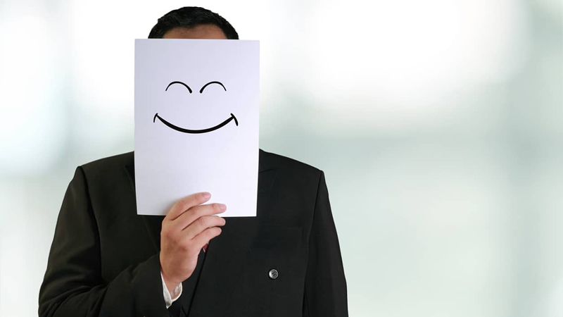 man holding paper in front of his face with a happy face on it