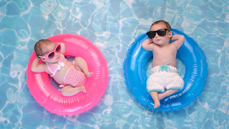 top view two babies reclining in pool tubes, girl in pink, boy in blue
