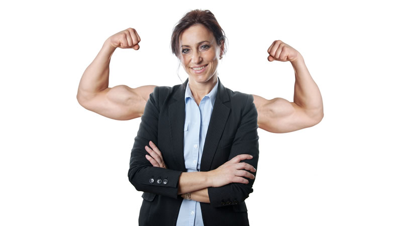 smiling woman in suit with arms crossed, bare muscular arms showing behind her