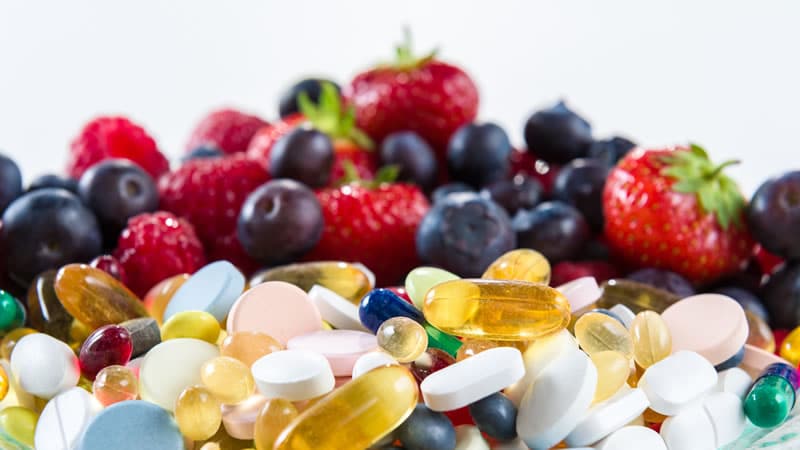 Pills, Capsules with fruit in background