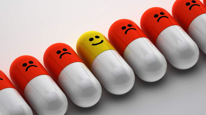 line up of capsules with happy faces, one sad face