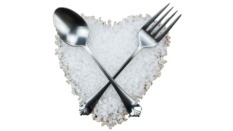 spoon and fork crossed over heart shaped pile of Himalayan Crystal Salt course grind