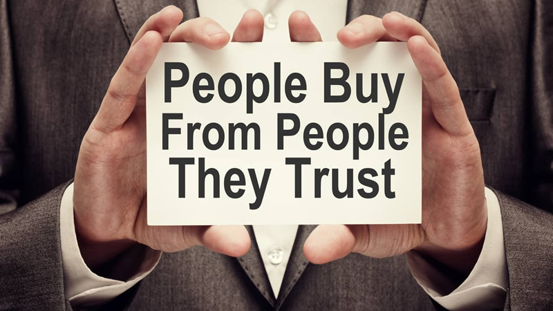 hands holding sign saying People Buy From People They Trust