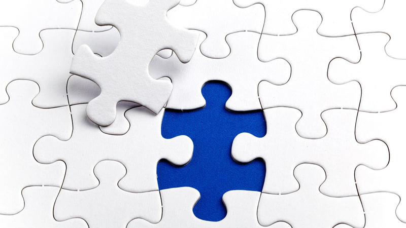 White jigsaw puzzle with one piece pulled out showing blue underneath
