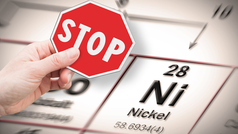 hand holding small STOP sign above periodic table Nickel