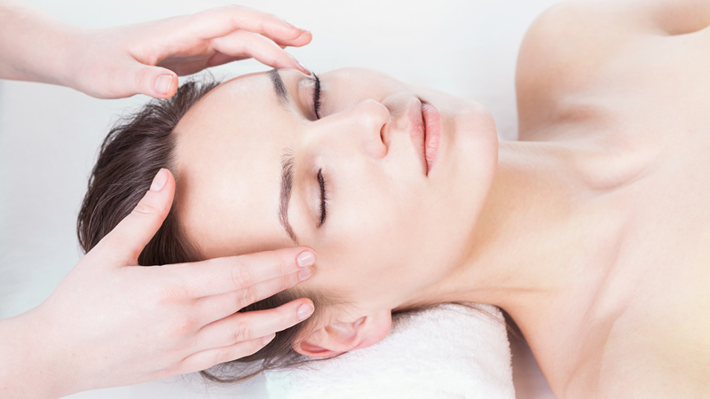 top view woman lying down with someones hands on her temples for treatment