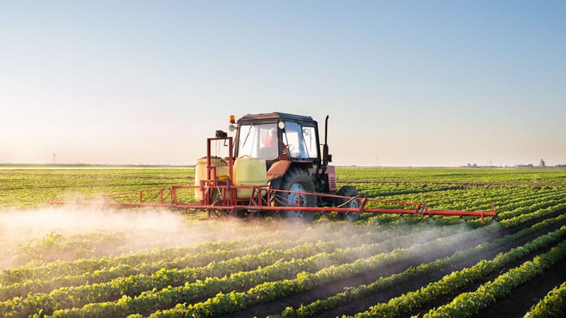tractor sprays crop of soybeans