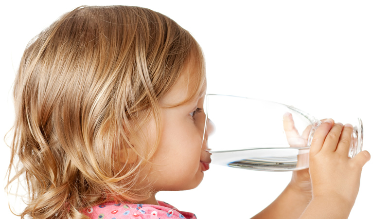 girl child drinking water from clear glass