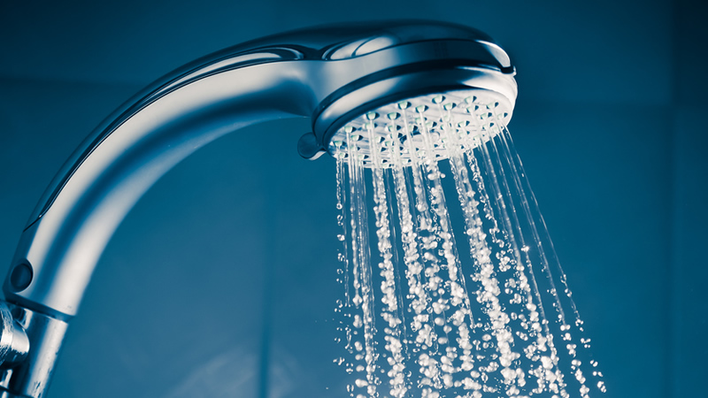 shower head spraying water on blue