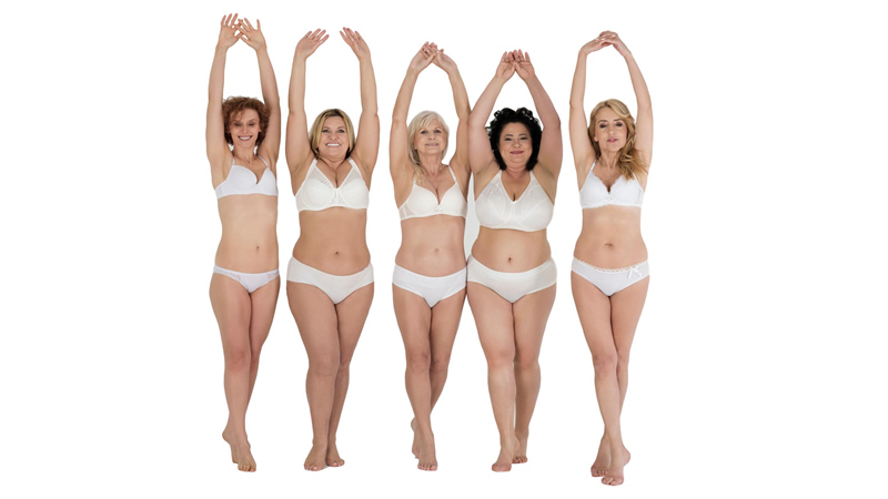 5 happy women of different shapes in underwear with arms up